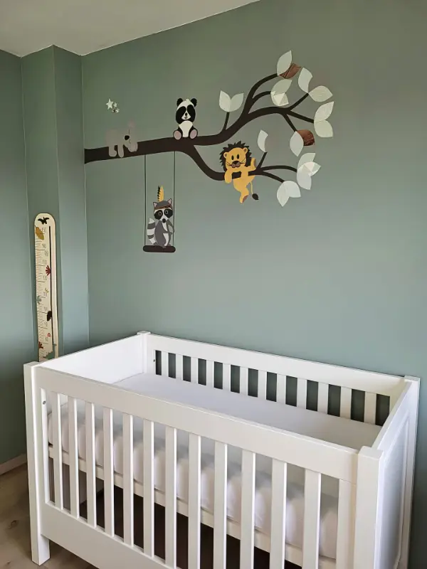 behangsticker met dieren op een tak in een zachtgroene babykamer